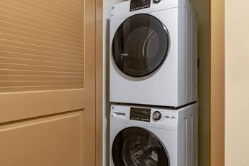 Two white front load washing machines stacked on top of each other.
